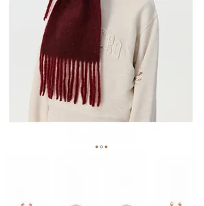 Detail of dark red knit scarf with tassels paired with a stylish distressed hoodie