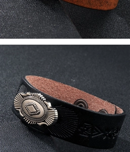 Dettaglio di un bracciale in pelle nera goffrata con ornamento metallico argento vintage