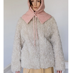Close-up of pink knitted balaclava hood paired with a beige faux fur textured jacket