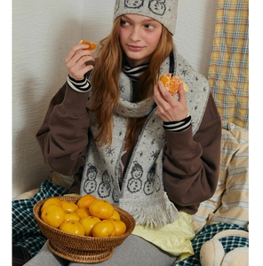Detailed close-up of grey knitted scarf and beanie with woven snowman and snowflake patterns