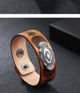 Dettaglio del bracciale in pelle vintage con medaglione in argento e chiusura a scatto