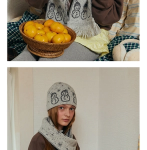 Detail of wool blend knit beanie and scarf featuring snowman pattern in warm home setting