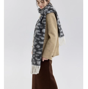 Detail of gray leopard print knit scarf with white long tassels on a wool-like winter wrap