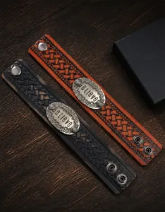 Dettaglio del bracciale in pelle vintage con placca in metallo incisa 'Believe'