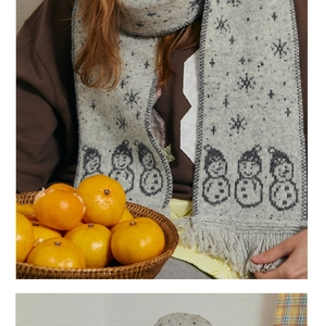 Close-up of grey wool blend scarf featuring jacquard snowman patterns and fringe