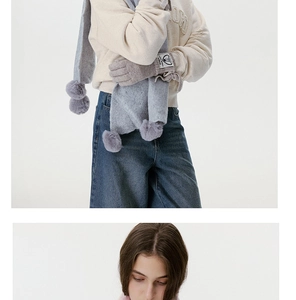 Details von grauem Strickschal mit Pompon und passenden Touchscreen-Handschuhen mit Logo
