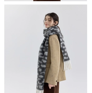 Detailed close-up of chunky leopard print knit scarf featuring long white fringe tassels