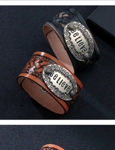 Dettaglio di bracciale in pelle vintage con placca in metallo incisa 'Believe' e trame