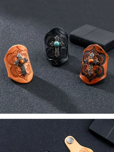Detail of leather rings with embossed patterns and metal crosses featuring turquoise stone