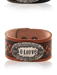 Dettaglio del bracciale vintage in pelle marrone con placca d'argento incisa con Believe