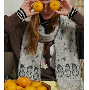 Detail of wool blend knitted scarf featuring snowman jacquard patterns and fringe edges