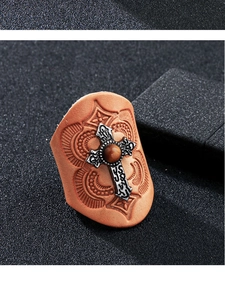 Macro detail of retro leather ring featuring embossed patterns and a silver cross with tiger eye stone
