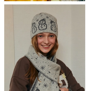Close-up of soft grey knit wool blend beanie and scarf set featuring cartoon snowman pattern
