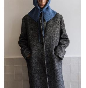 Detail of grey herringbone wool coat styled with a blue chunky knit balaclava hood