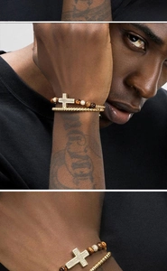 Detalle de un set de pulseras para hombre con cruz de circón dorado y cuentas de ojo de tigre