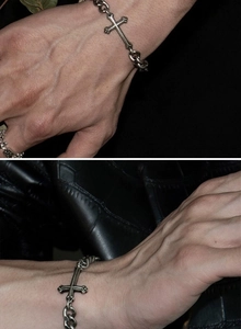 Macro view of vintage silver cuban chain bracelet featuring a gothic cross pendant