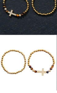 Detalle de cuentas de ojo de tigre y colgante de cruz dorada con circonitas en la pulsera