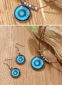Détail de parure bohème avec pendentifs mandala bleus posés sur une surface en bois naturel