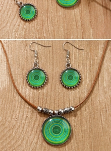 Détail du collier et des boucles d'oreilles mandala bohème sur fond bois clair