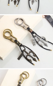 Macro detail of retro bronze trident keychain with leather rope on a wooden desk