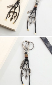 Macro view of bronze and silver Neptune trident keychain pendants with leather cords