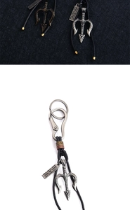 Detailed macro view of vintage bronze trident keychain with woven leather and carabiner