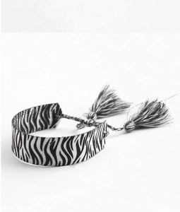 Détail d'un bracelet tissé à la main motif zèbre noir et blanc avec glands en coton