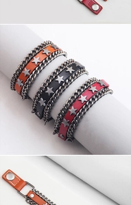 Dettaglio di bracciali punk in pelle con stelle e catene in metallo in tre colori