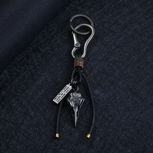 Vintage leather keychain with raven skull pendant and engraved quote tag on dark background