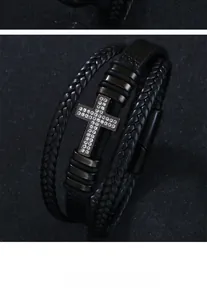 Detail of multi-layer black braided leather bracelet with rhinestone inlaid cross charm