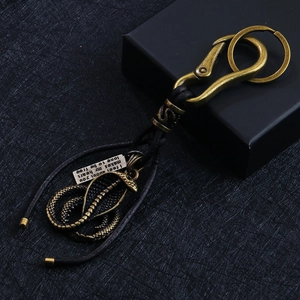 Vintage cobra metal keychain with woven strap and engraved tag on a gift box