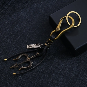Retro bronze trident keychain with leather rope and engraved tag on black background