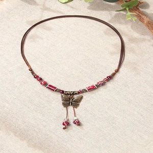 Retro butterfly ceramic necklace on beige linen background with natural dried flower