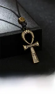Detailed macro of vintage alloy Ankh cross pendant with relief wings and wax cord