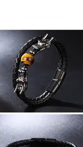 Detail of double-layer black braided leather bracelet with silver dragon heads and tiger eye stone
