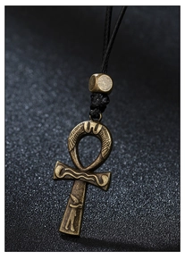 Macro shot of bronze Ankh cross pendant with ancient Egyptian motifs on black woven cord