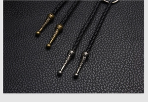 Macro detail of engraved metal bolo tie tips in antique bronze and silver finishes