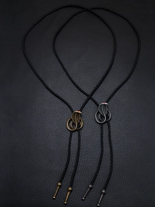 Detail of cobra bolo ties with red gemstone eyes on black braided leather cords