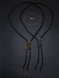 Close-up of vintage cobra bolo ties in bronze and silver finish with woven leather cord