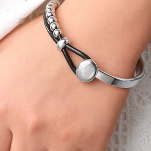 Dettaglio macro del bracciale bohémien a doppio strato in pelle e perline argentate al polso