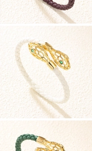 Détail macro du fermoir tête de serpent dorée avec gemmes vertes sur bracelet tressé