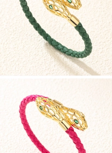 Détail de bracelets serpent tissés avec têtes de serpent dorées et yeux en pierre verte