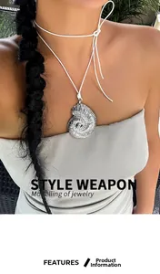 Close-up of a silver conch shell pendant on a white adjustable cord worn by a model