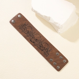 Punk style wide brown leather bracelet featuring embossed skull and flame patterns