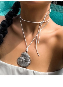 Detail shot of a silver nautilus shell pendant on a white cord worn poolside