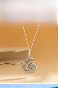 Close-up of silver nautilus pendant with spiral texture on a simple white cord