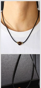 Détail macro d'une perle en œil de tigre naturel sur un collier en cordon noir