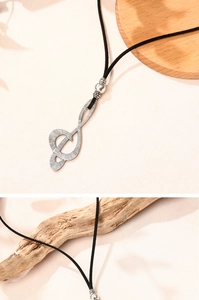 Macro shot of musical note pendant with vintage silver texture and black velvet cord