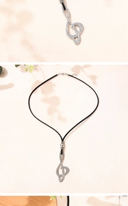 Detailed view of a vintage silver musical note pendant on a black cord necklace