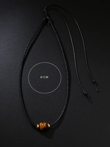 Détail d'une perle en œil de tigre naturelle sur un collier cordon noir de 81 cm